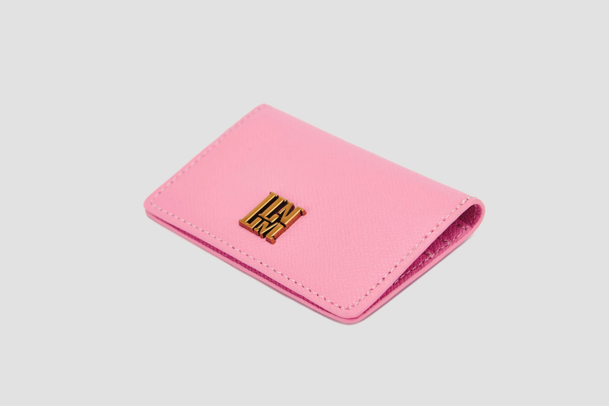 Pink textured leather  wallet with gold logo and magnetic closure.