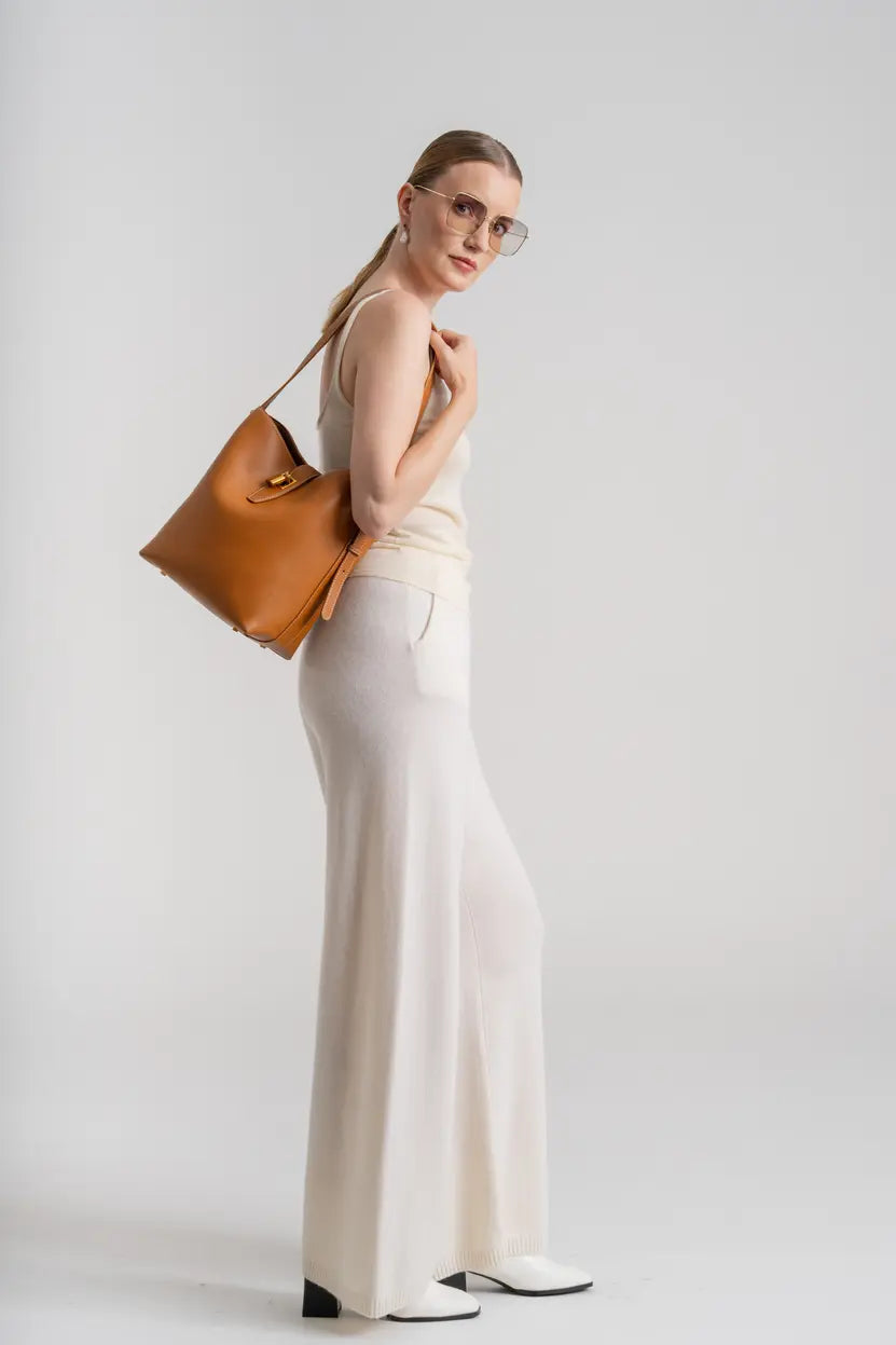 Woman in a chic white outfit carrying a big tan leather hobo bag