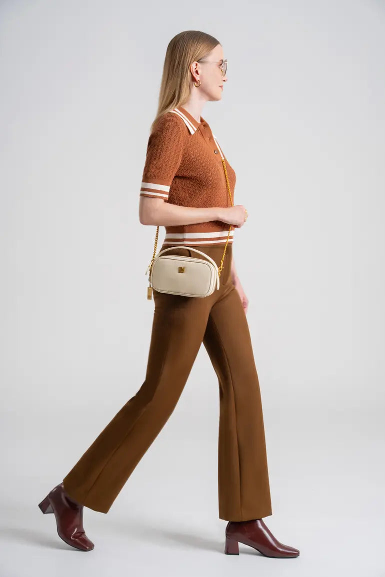 Woman in stylish brown outfit carrying a designer cream leather crossbody bag with long strap