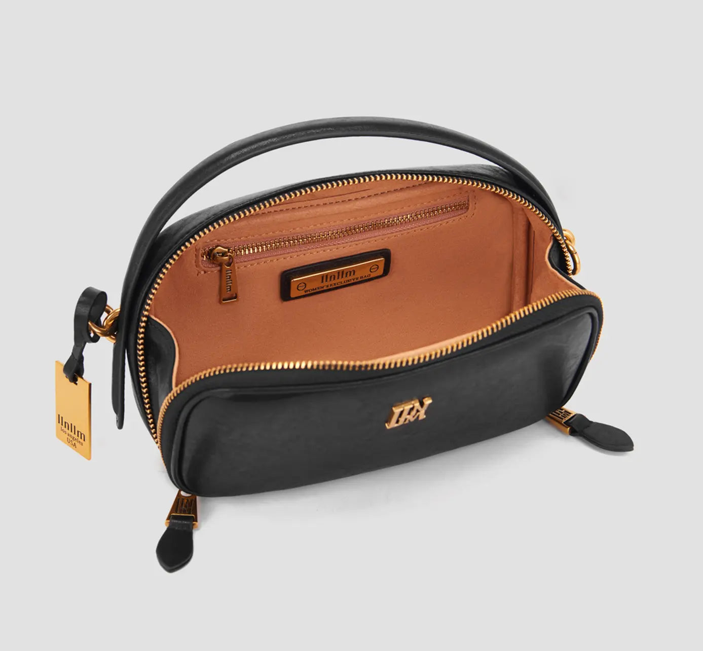 The black leather bag interior has a zip pocket and tan lining. It is a compact women’s handbag with practical storage.