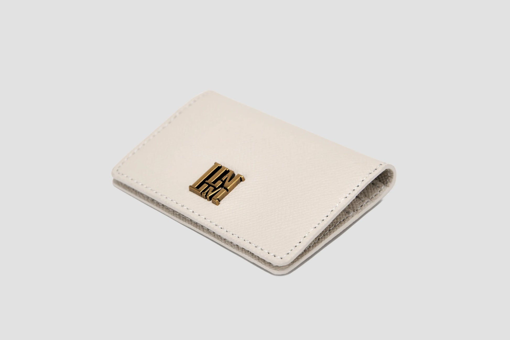 White textured leather  wallet with gold logo and magnetic closure.