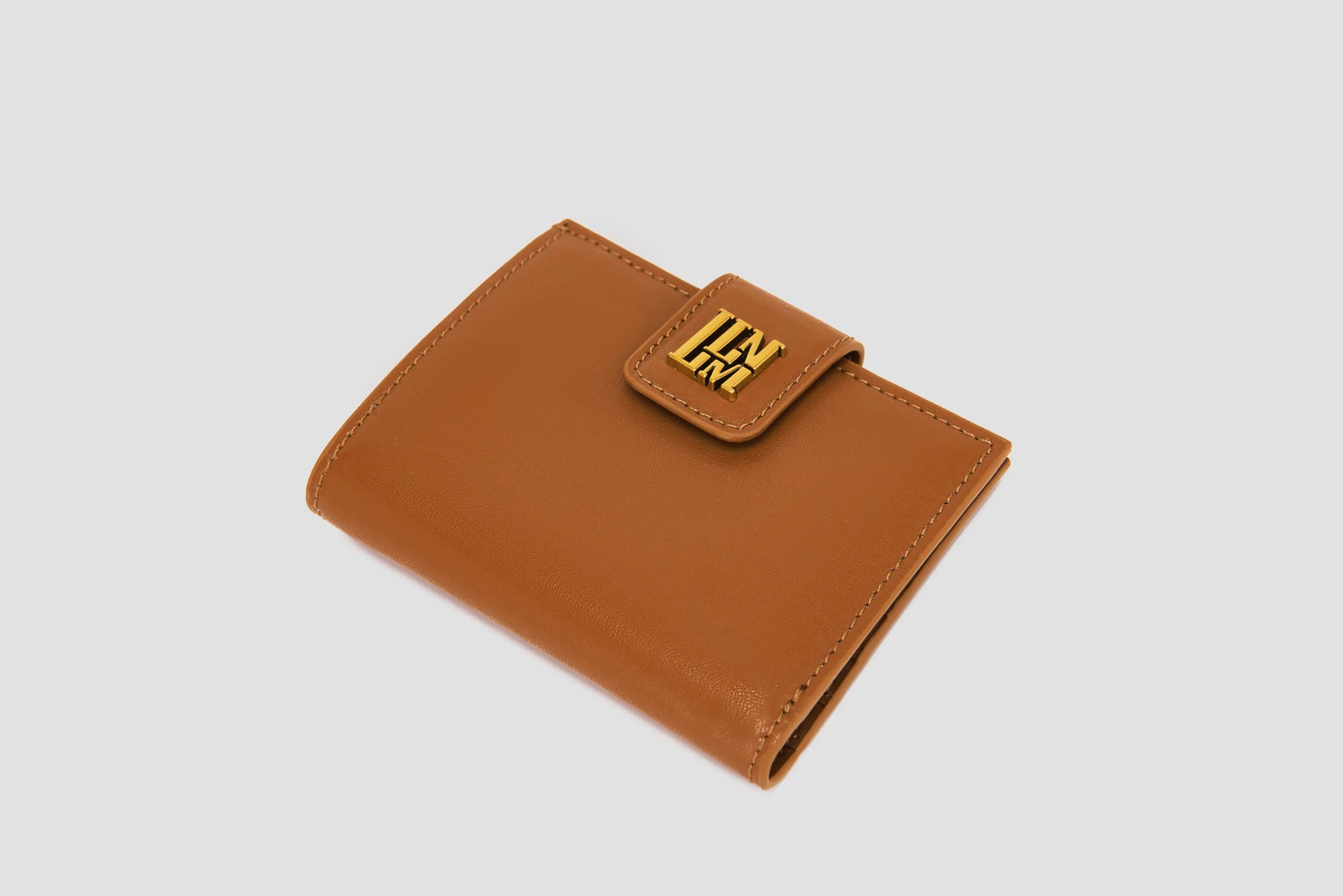 The angled view of tan llnllm wallet showing gold logo snap closure.