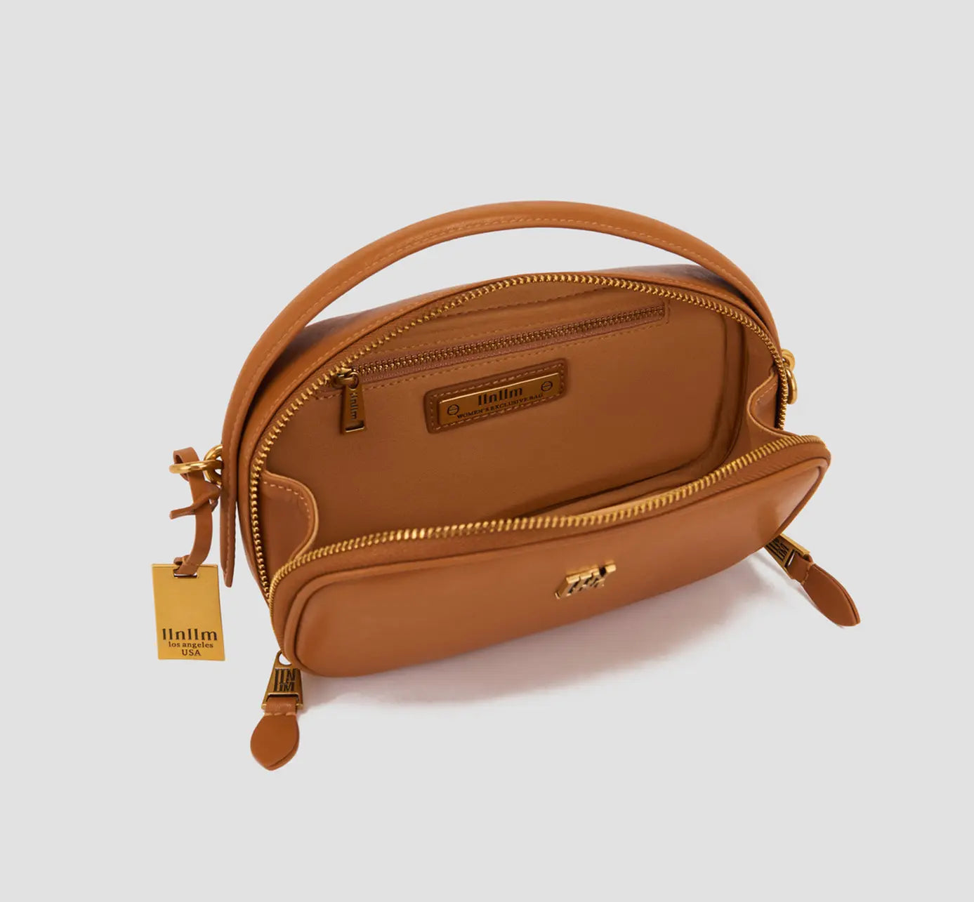 The Interior view of a tan leather crossbody bag – a compact women’s purse with a zipper pocket and designer lining, a functional small handbag.