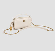 This is an angled view of a chic white compact crossbody bag for women with a gold chain strap — a minimalist square mini-shoulder bag.