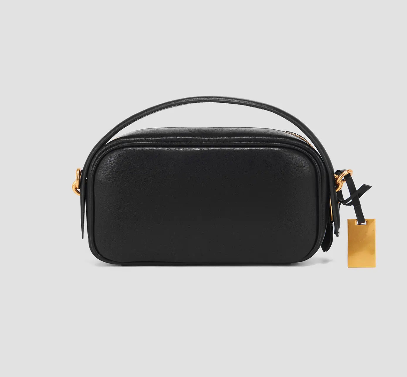 The back view of a black crossbody handbag with a handle and gold tag- minimalist black crossbody bag with clean leather and designer label – lightweight travel purse for women.
