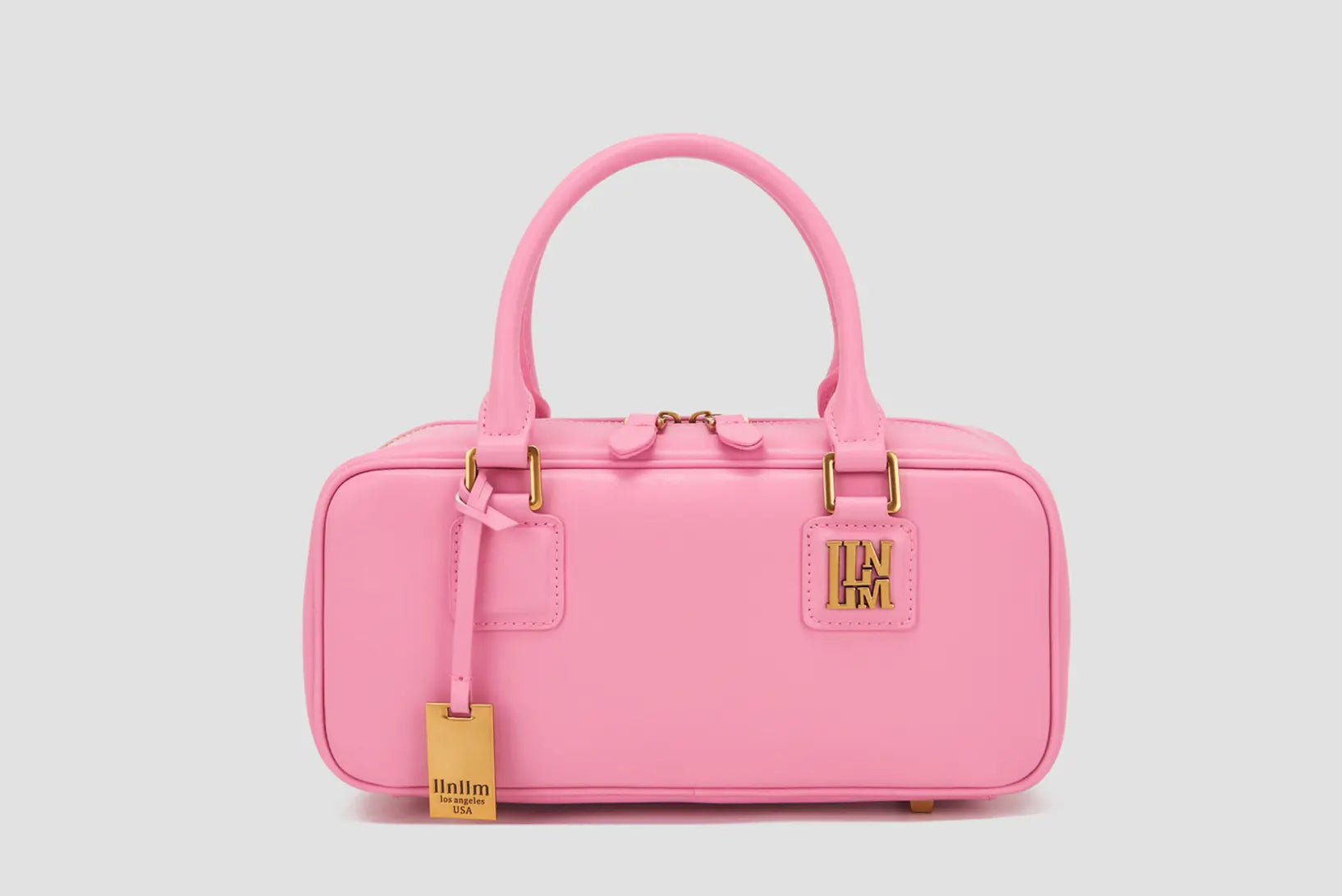 This is the front view of a pink rectangular handbag with top handles and a gold logo— an affordable luxury purse by the Los Angeles-based fashion brand llnllm.