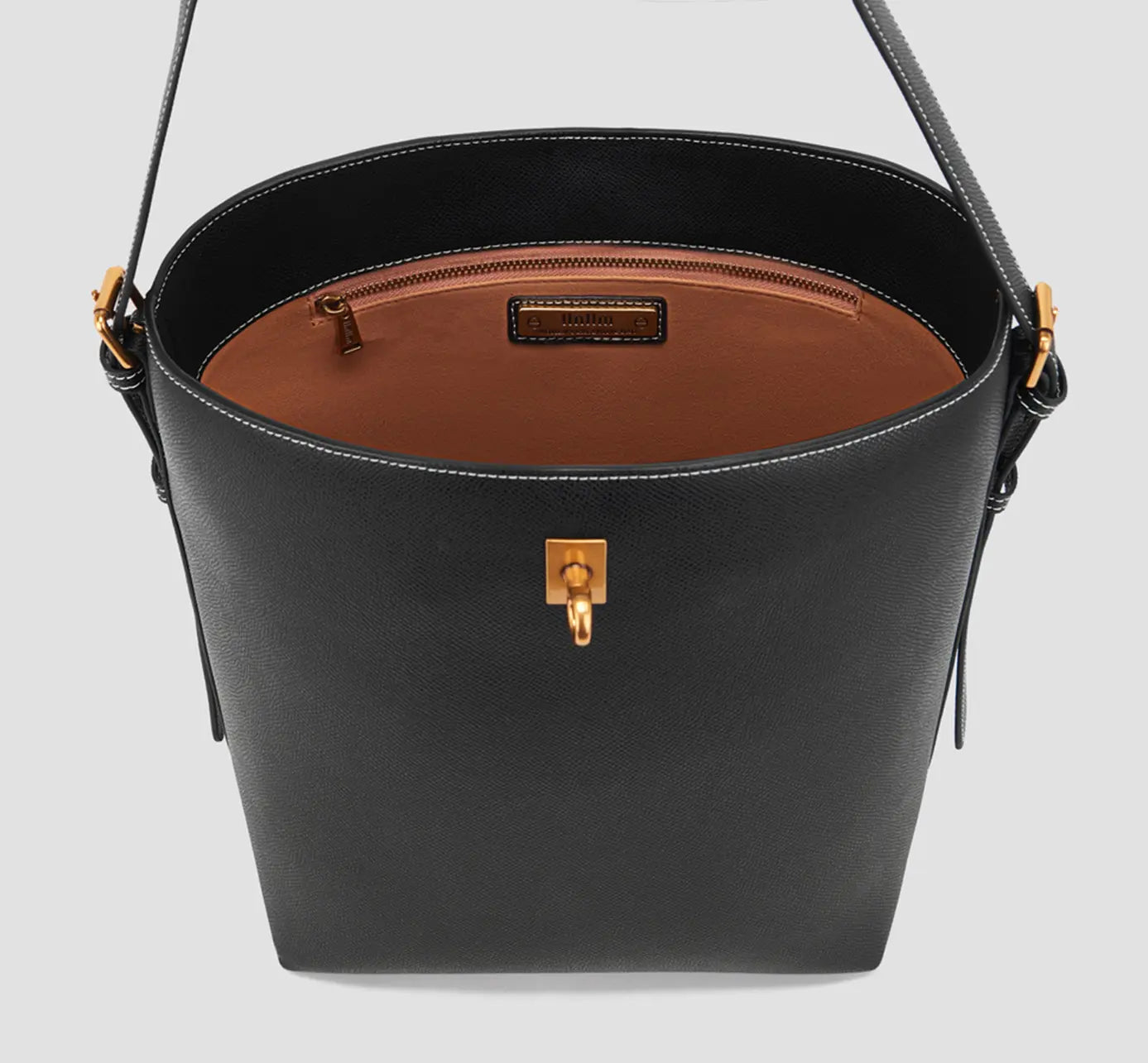 Top Interior View of Spacious interior of black bucket bag with brown lining, zip pocket, and premium stitched edges.

