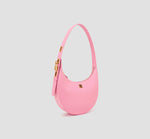 The angled front of chic crescent pink handbag with adjustable strap – elegant and minimalist leather bag for casual or evening wear.
