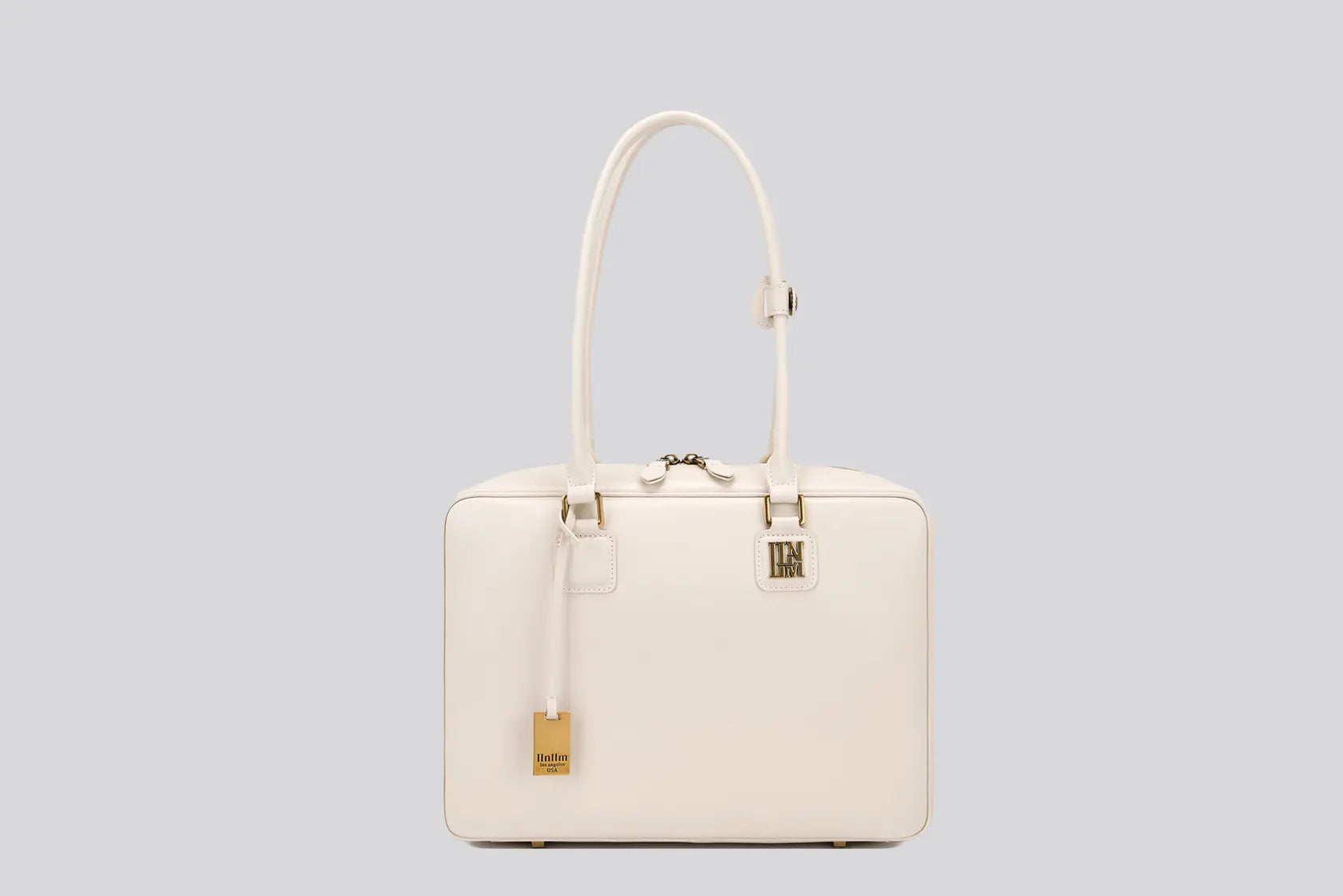 The front view of a white leather structured handbag with gold hardware—an elegant tote bag for women by Los Angeles fashion brand llnllm.
