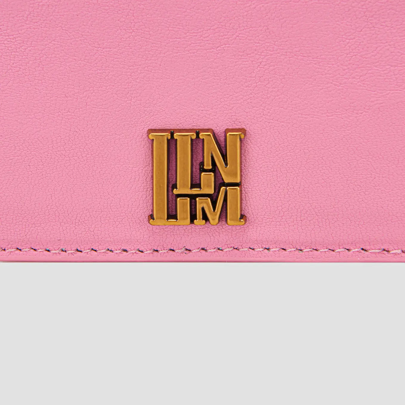 Pink leather llnllm slim card holder with gold logo, minimalist design.