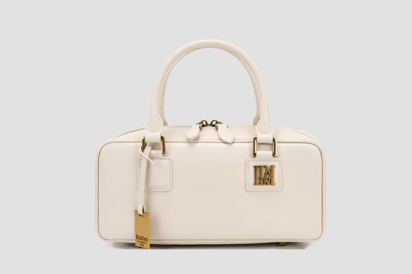 The front view of elegant white top handle handbag with gold hardware logo tag.