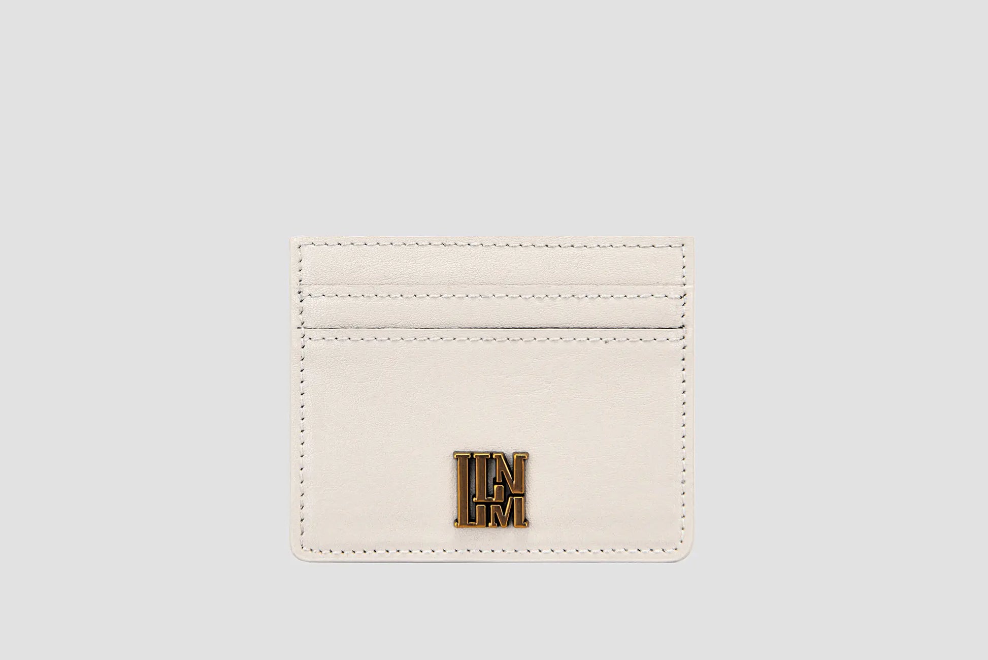 White leather llnllm slim card holder with gold logo, modern style.