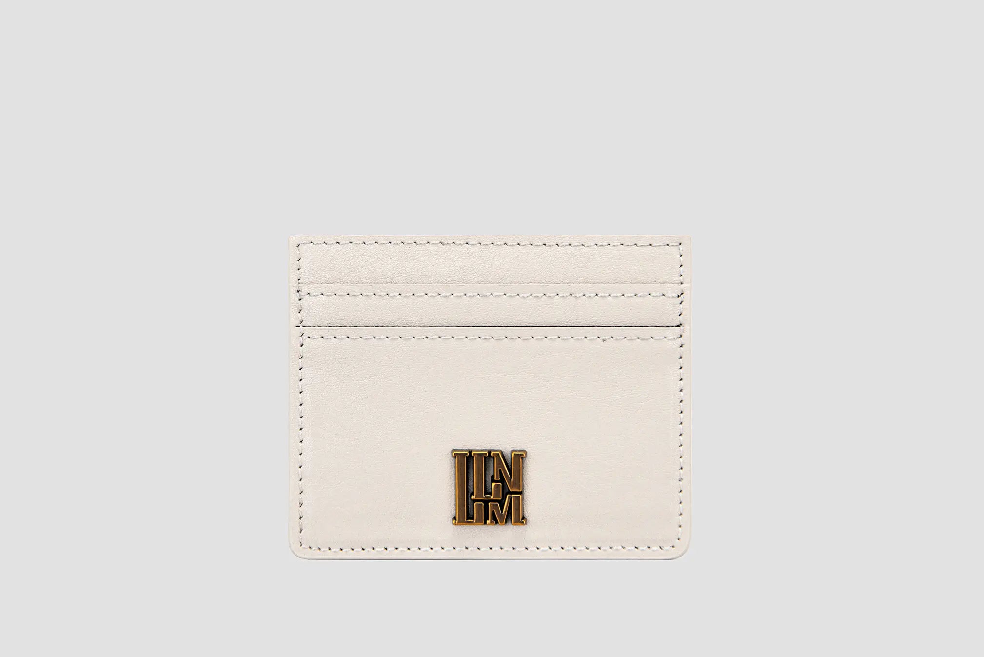 White leather llnllm slim card holder with gold logo, modern style.