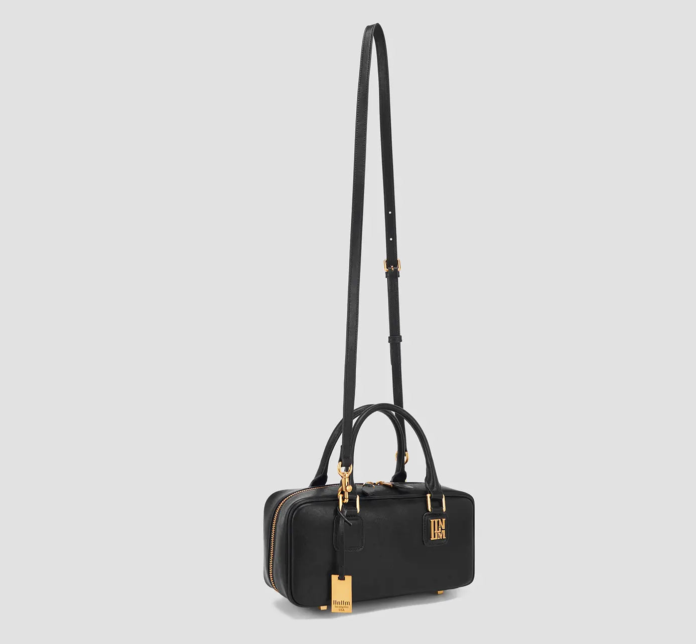 Angled with long strap upright):
This black structured handbag has an adjustable crossbody strap and gold hardware.

